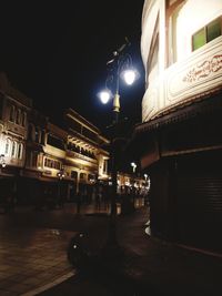 Illuminated street amidst buildings at night