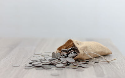 Close-up of coins spilling from sack on table