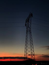 Low angle view of silhouette electricity pylon against sky during sunset