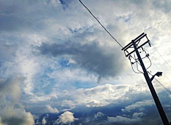 Low angle view of power lines against cloudy sky