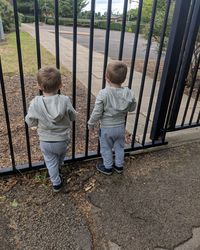 Rear view of boys standing by metal gate