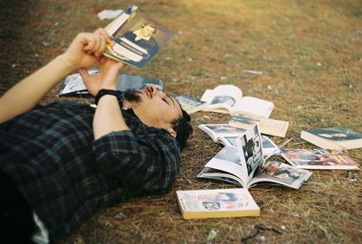 High angle view of man reading book while relaxing on field