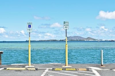 Road sign by sea against sky