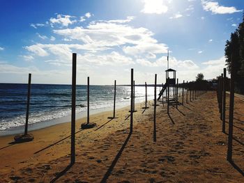 Wooden posts on beach against sky