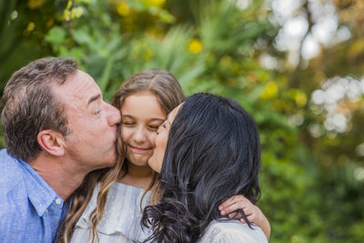 Parents kissing their young daughter