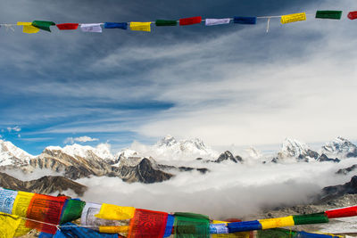 Multi colored flags on snowcapped mountains against sky