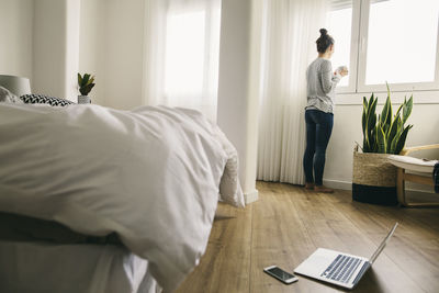 Woman looking out of bedroom window