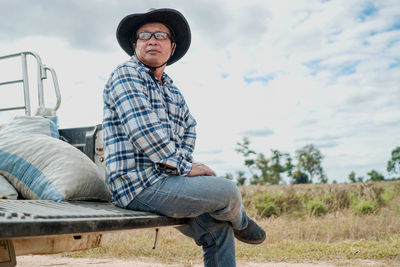 Man, elderly, farmer, wearing a hat, sitting in the trunk of a farm vehicle, close-up