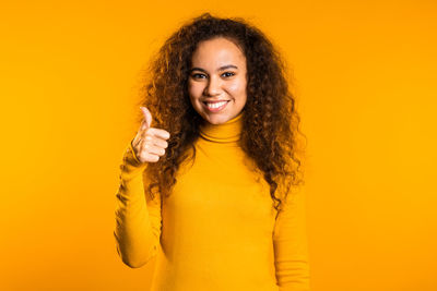 Portrait of a smiling young woman against yellow background