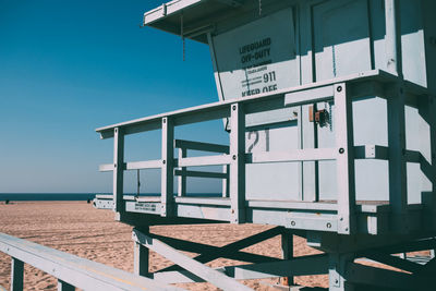 Information sign on beach against clear blue sky