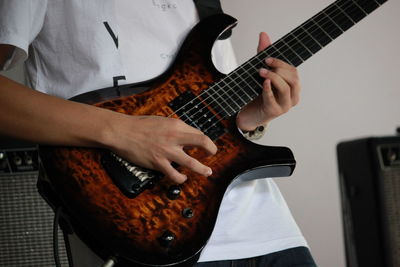 Midsection of man playing guitar at home