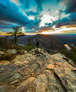 Rear view of man standing on rock against sky