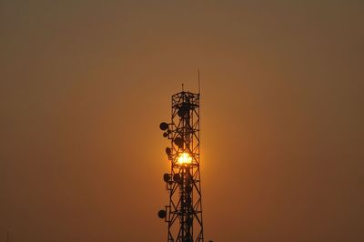 Low angle view of silhouette communications tower against sky during sunset