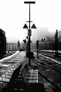 Railroad tracks by street against sky in city