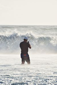 Rear view of man in sea against sky