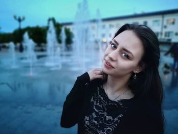 Portrait of beautiful woman standing against fountain