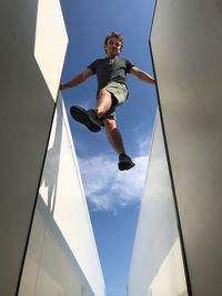 Low angle view of man jumping against sky