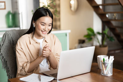 Young woman using mobile phone while sitting on table