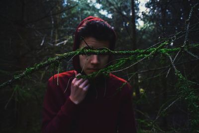 Moss covered twigs against young man standing in forest