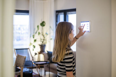 Girl using digital tablet mounted on wall at modern home