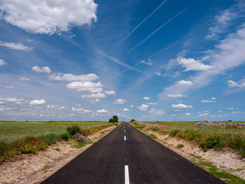 Road leading towards landscape against sky