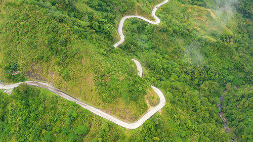 Mountain curve road passing along the slopes of mountains and hills covered with green forest 