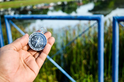 Cropped hand of person holding navigational compass at park