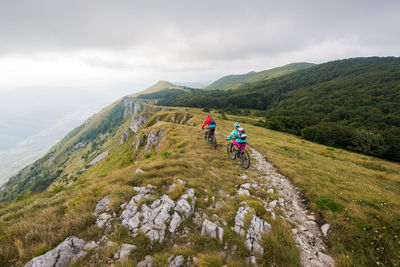 Rear view of people riding bicycles on mountain