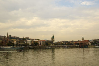 River by buildings against sky during sunset