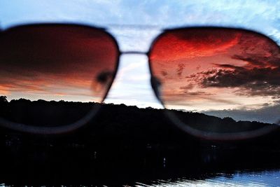 Close-up of sunglasses against sky during sunset