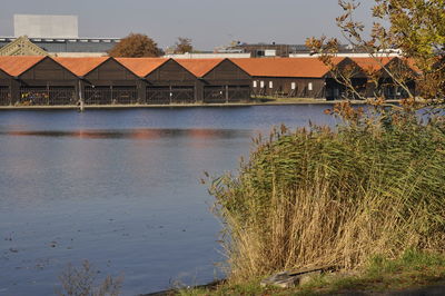 Houses by lake and buildings against sky