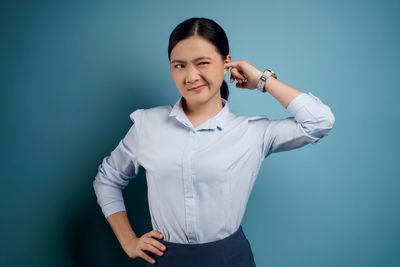 Portrait of a smiling young woman against blue background