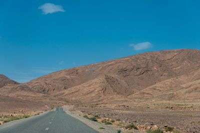 Road amidst desert against blue sky