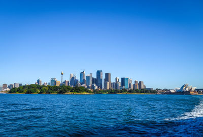 Sea by buildings against clear blue sky