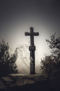 Cross in cemetery against sky