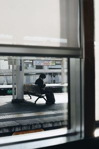 Woman seen through window sitting at railroad station