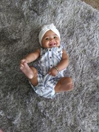 High angle portrait of smiling girl lying on carpet