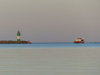 Lighthouse on sea against clear sky