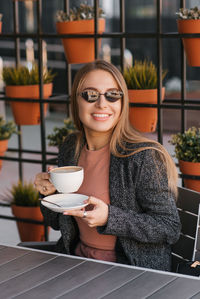 Beautiful smiling woman drinking coffee at cafe. portrait of mature woman in a cafeteria drinking