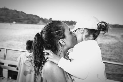 Mother kissing her daughter by sea