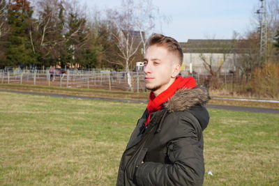 Young man looking away while standing in park