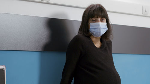 Portrait of pregnant woman wearing mask sitting at hospital