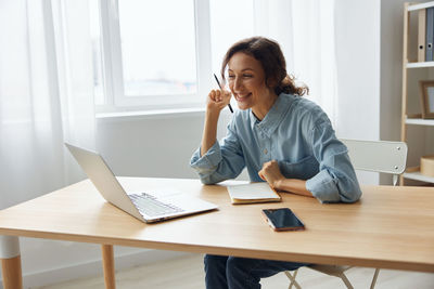 Smiling businesswoman doing video on laptop at desk in office