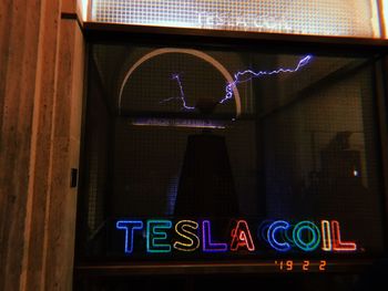 Low angle view of illuminated sign on glass at restaurant