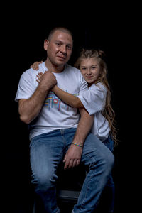 Portrait of mother and daughter against black background