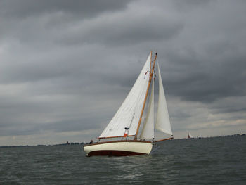 Boats sailing in sea against cloudy sky