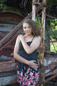 Portrait of young woman standing against wall