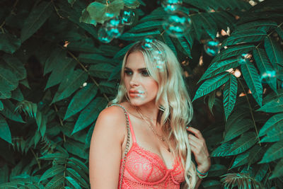 Close-up of bubbles by woman looking away standing against plants