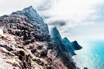 Rock formations by sea against sky