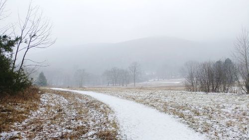 Snow covered landscape against sky during winter